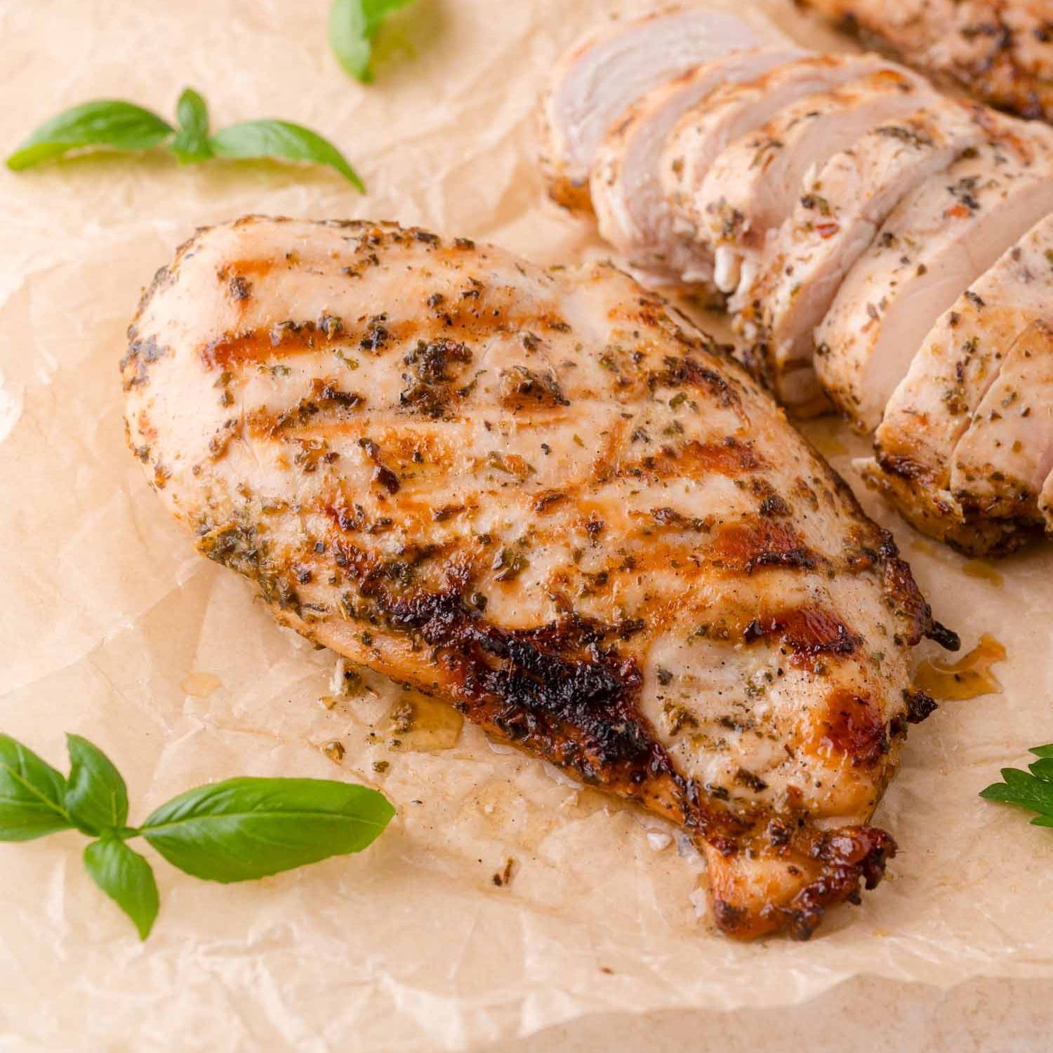 Marinated, grilled chicken breast on brown parchment paper.