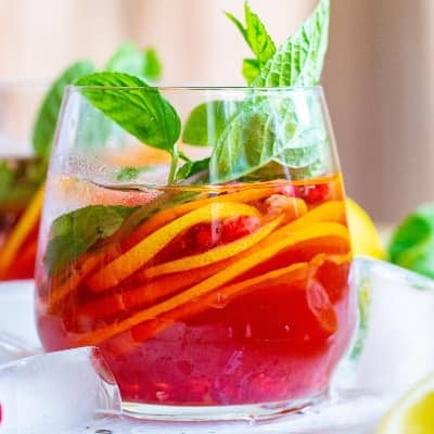 Bright red punch with citrus slices and mint leaves.