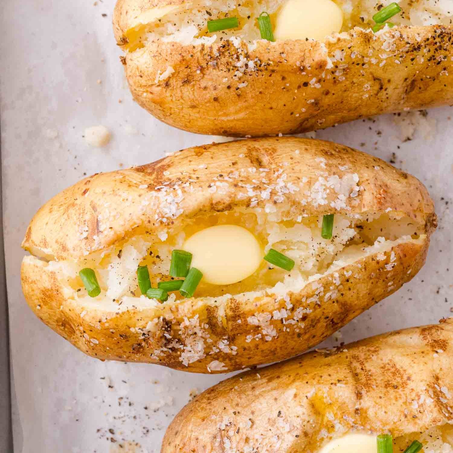 Baked potatoes, sprinkled with salt, split open in the middle and topped with butter and chives.