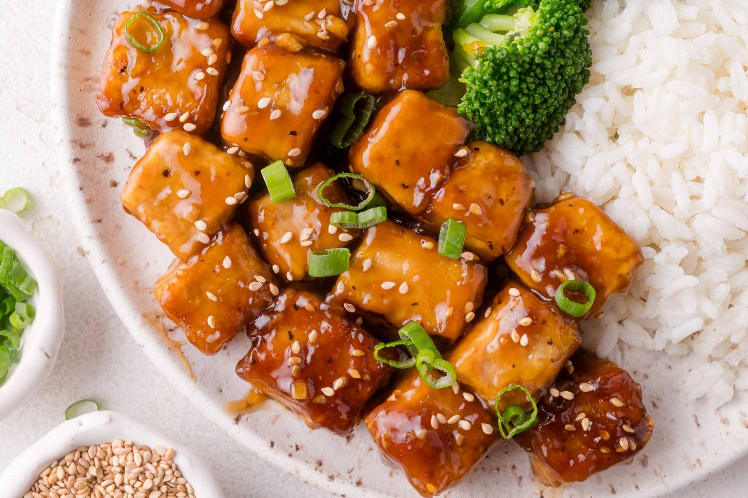 Glossy teriyaki tofu cubes with broccoli and steamed white rice.