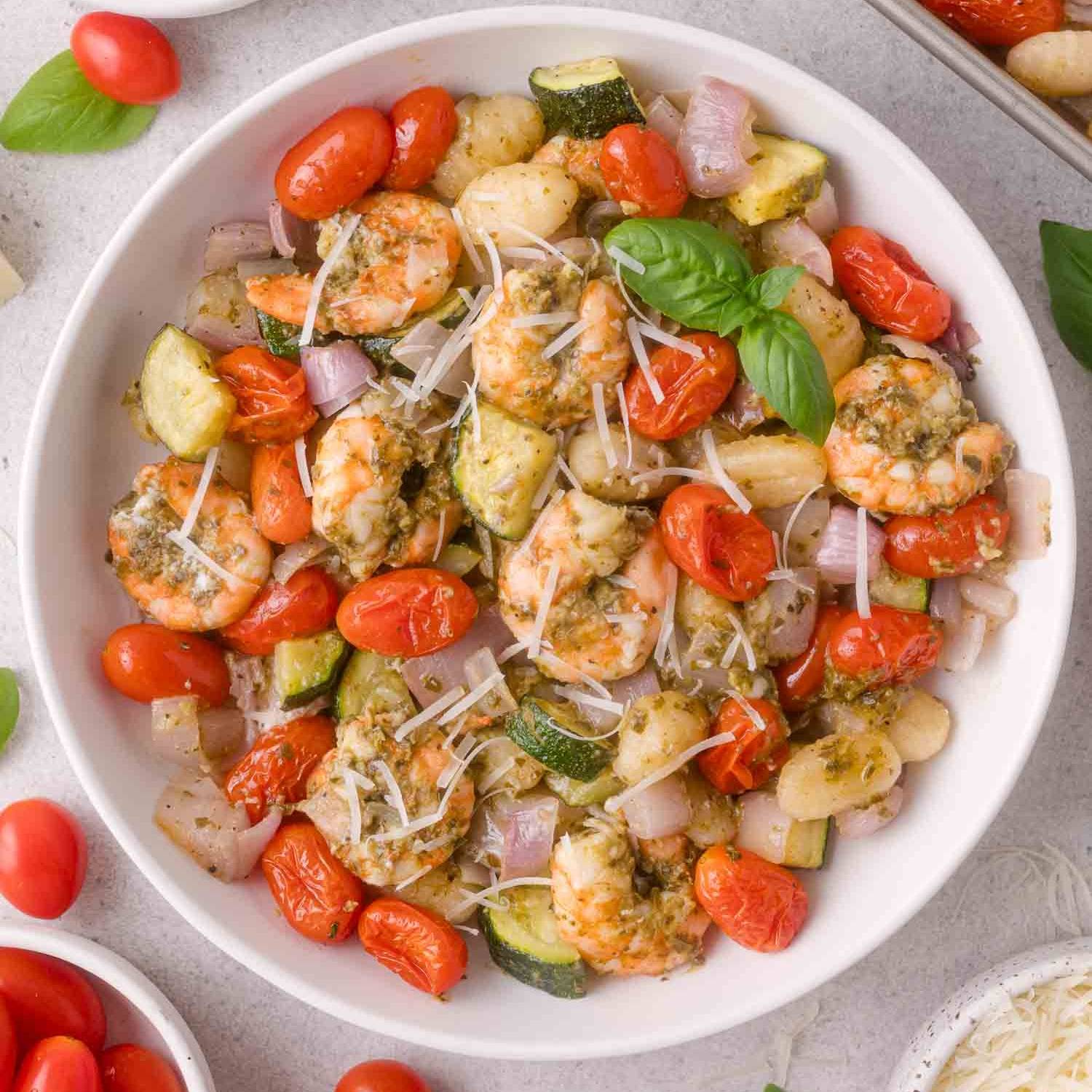 Shrimp, tomatoes, zucchini, shallots, all in a bowl tossed with pesto.