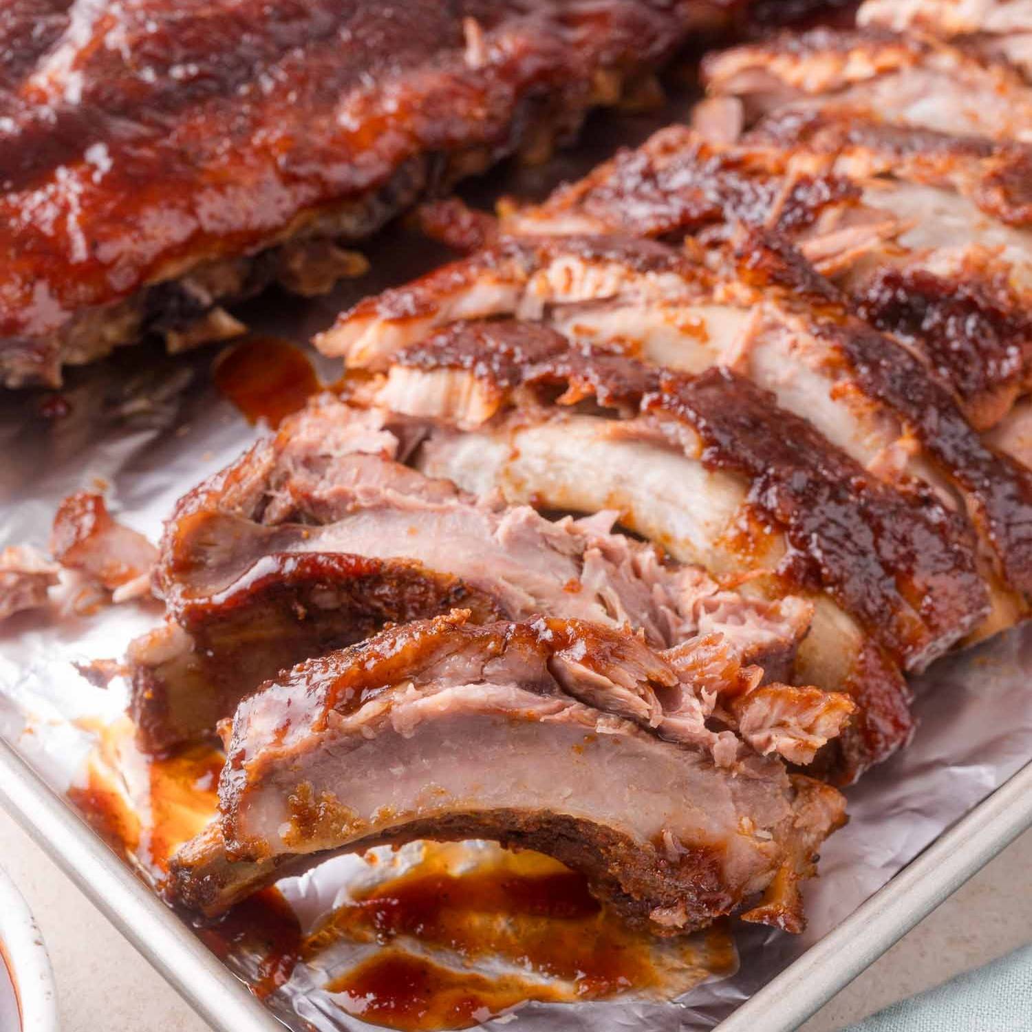 Ribs, cut to show the meat falling off the bone, topped with bbq sauce.