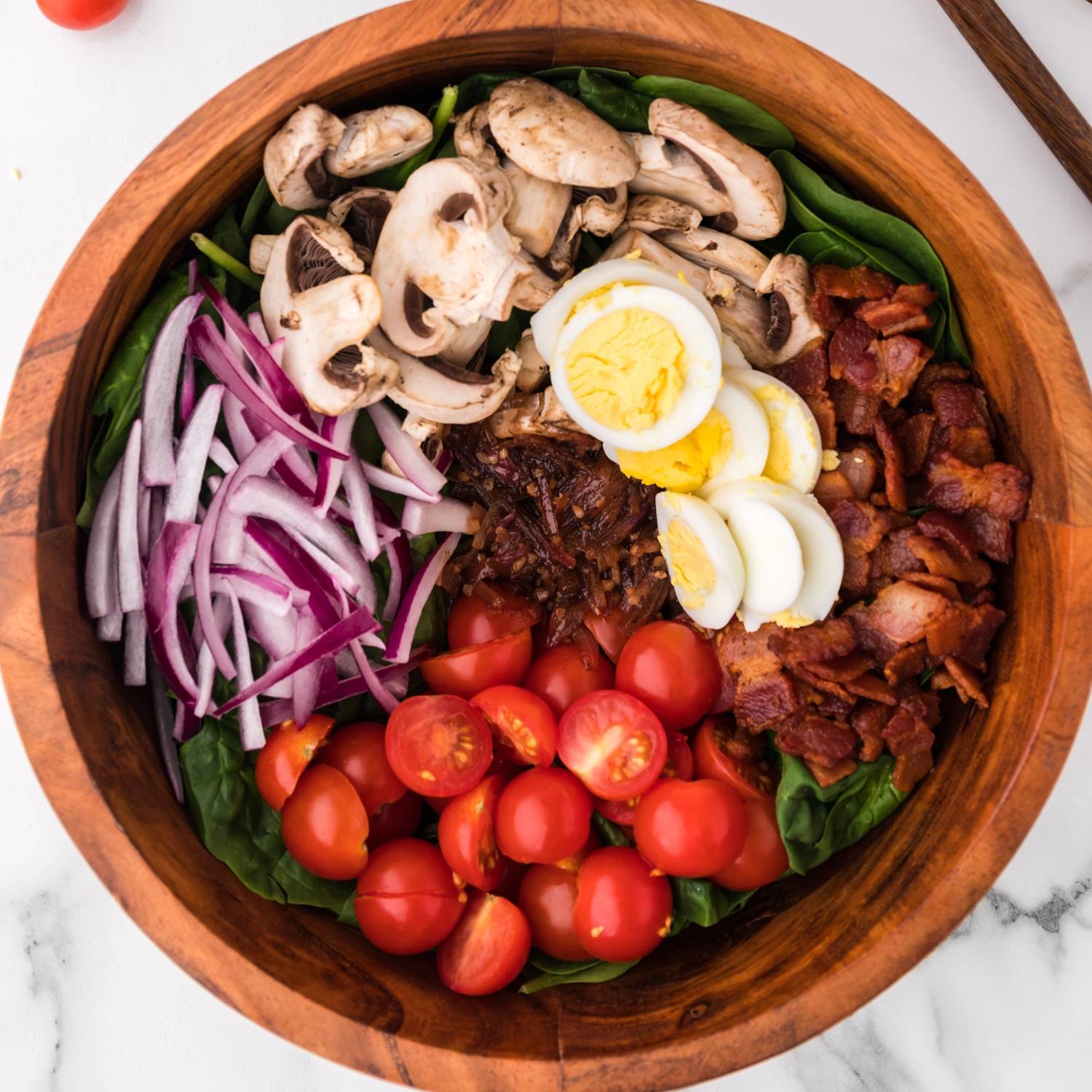 Spinach topped wtih bacon, eggs, mushrooms, tomatoes, onion, and salad dressing.