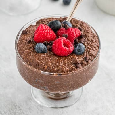 Chocolate chia seed pudding in a pedestal glass bowl, topped with fresh berries.