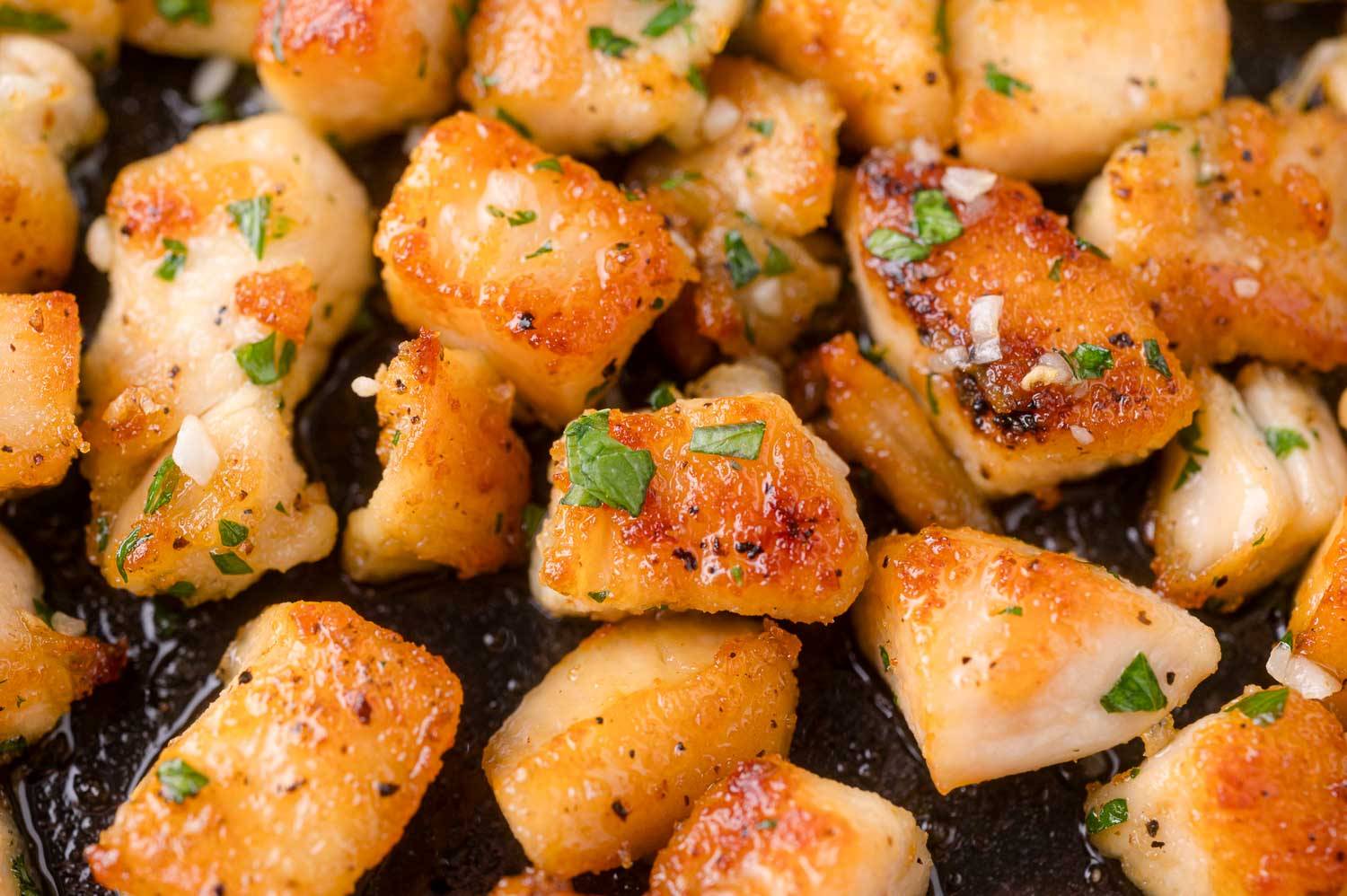 Close up of garlic butter chicken bites, garnished with parsley.