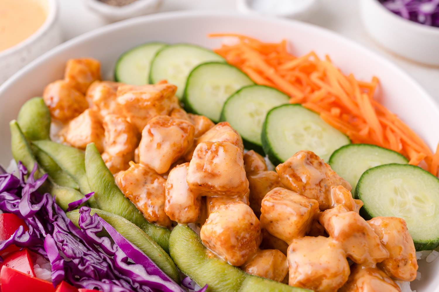 Bang bang chicken in a bowl with fresh vegetables and rice.