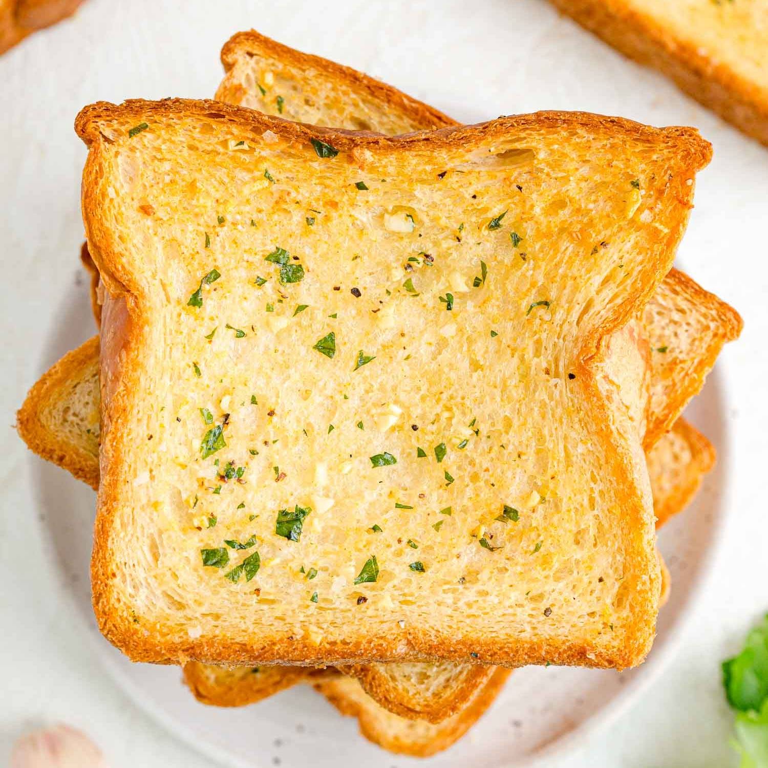 Texas toast garlic bread stacked on a white plate.