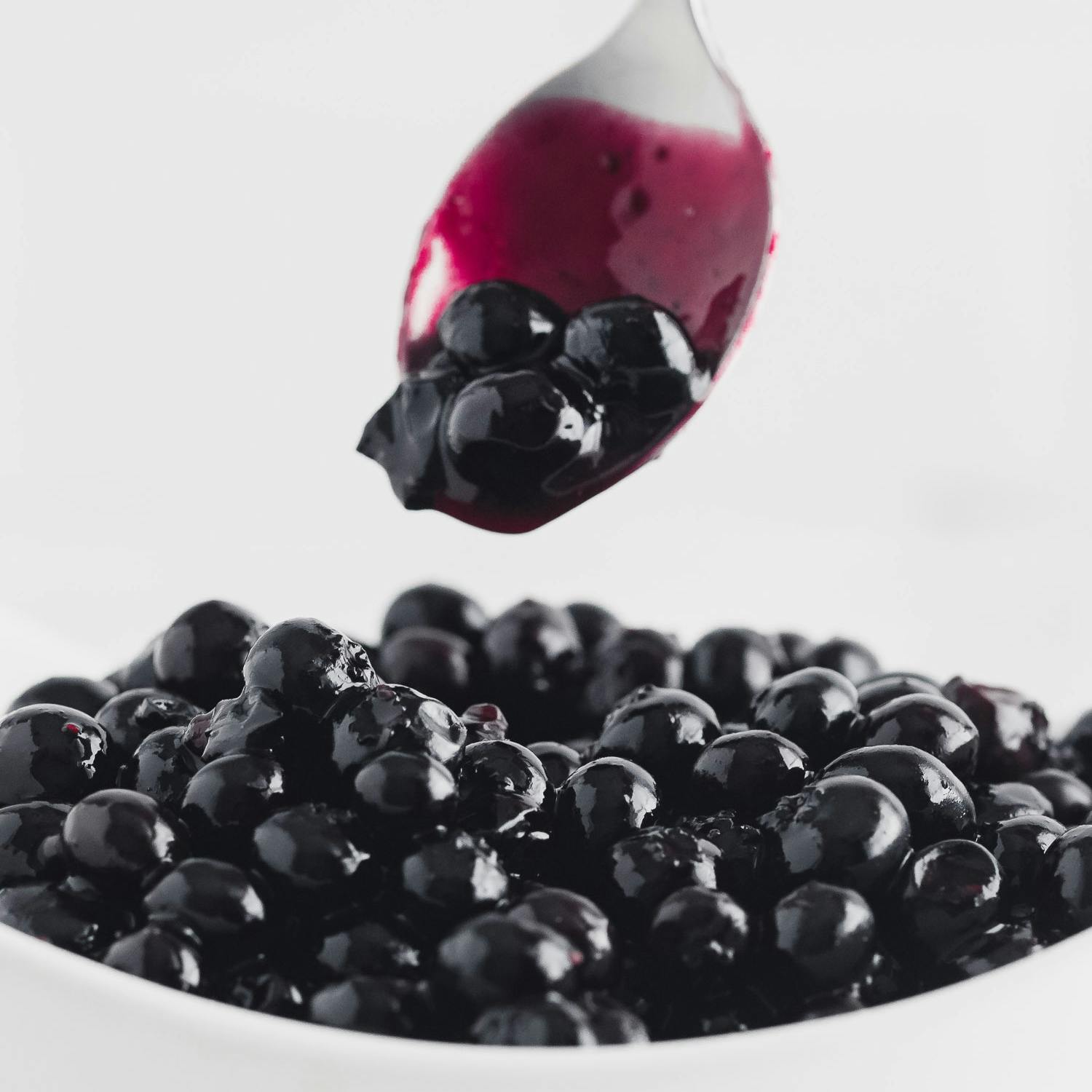 Blueberry sauce in bowl and on spoon.