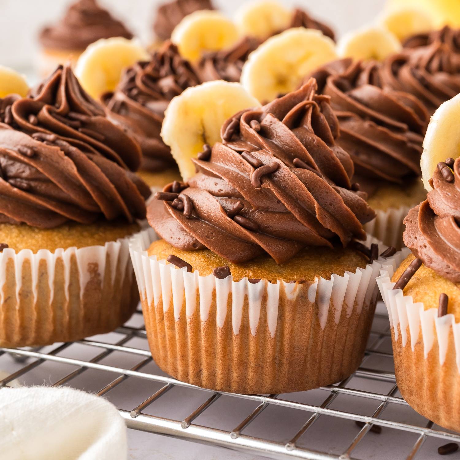 Banana cupcakes with chocolate frosting, on a cooling rack.