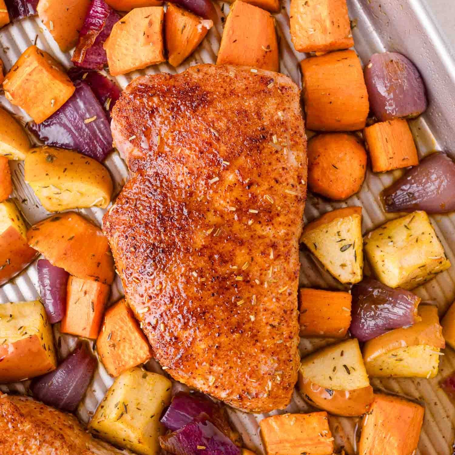 Sheet pan pork chop surrounded by sweet potatoes, apples, onions.