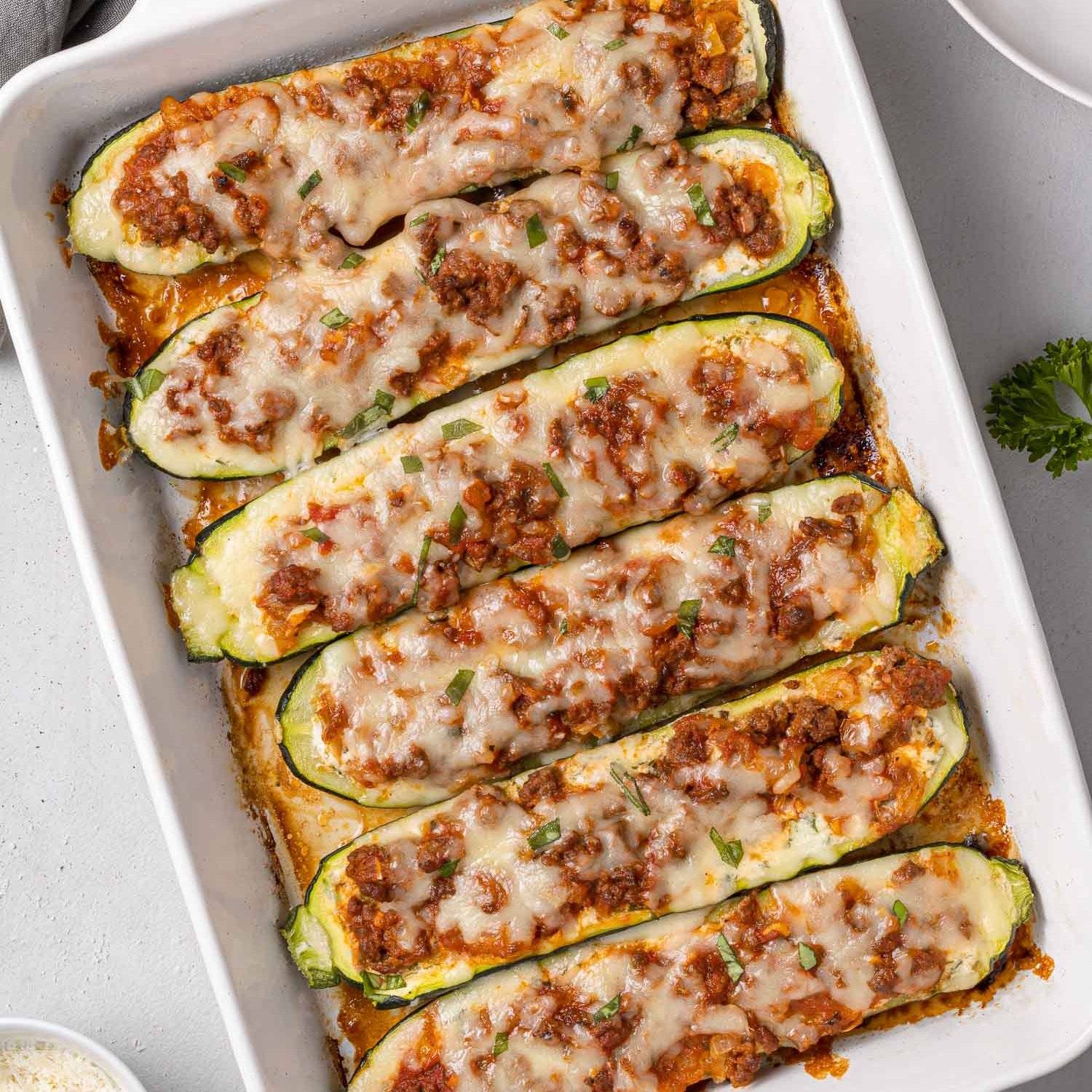 Lasagna zucchini boats in a white casserole dish.
