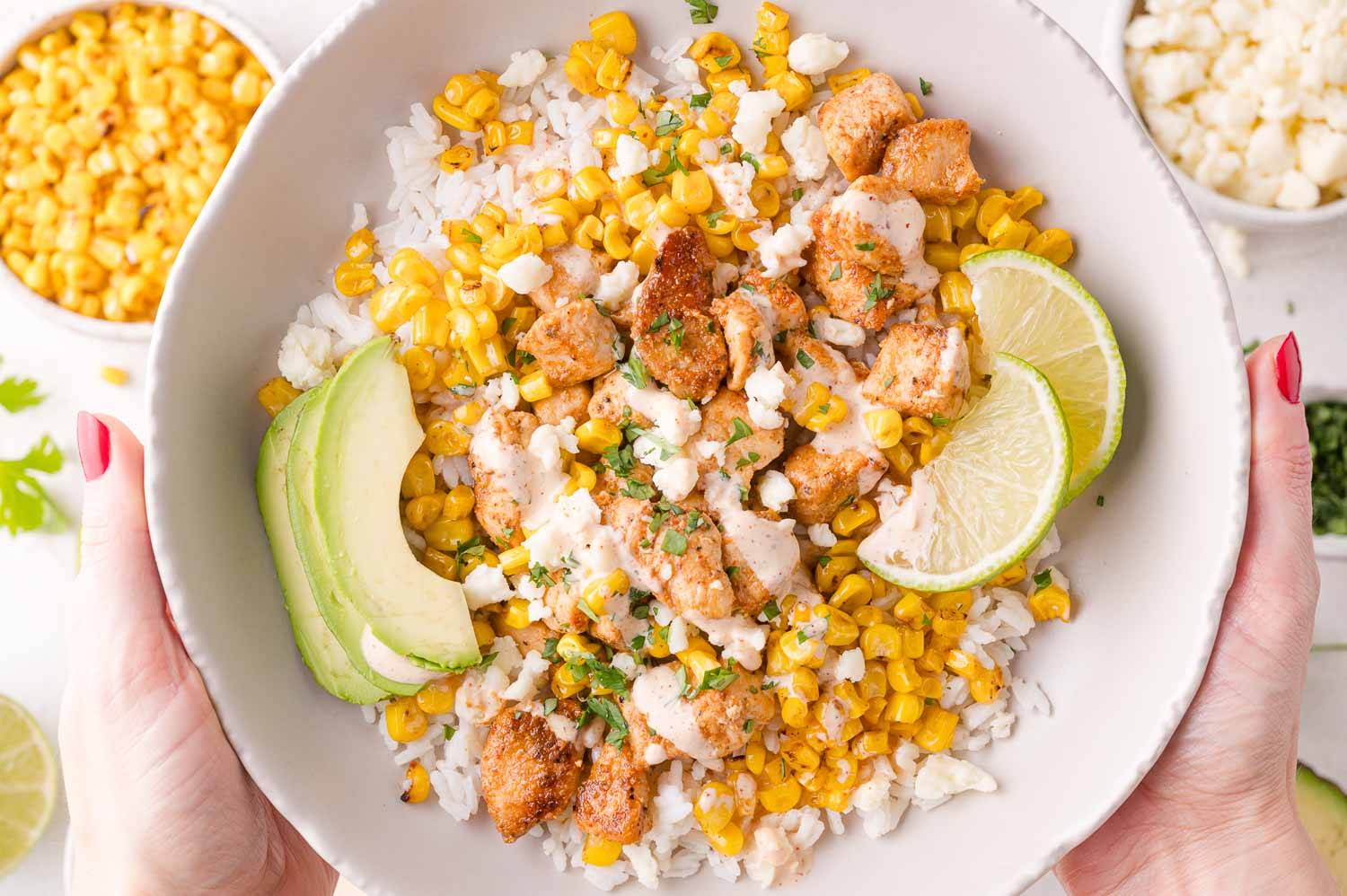 Street corn chicken bowl, held with two hands.