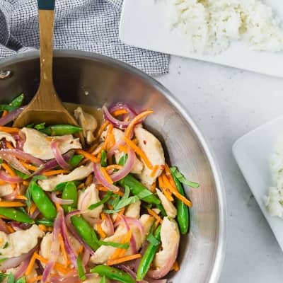 Stir fry in a pan, plates of rice nearby