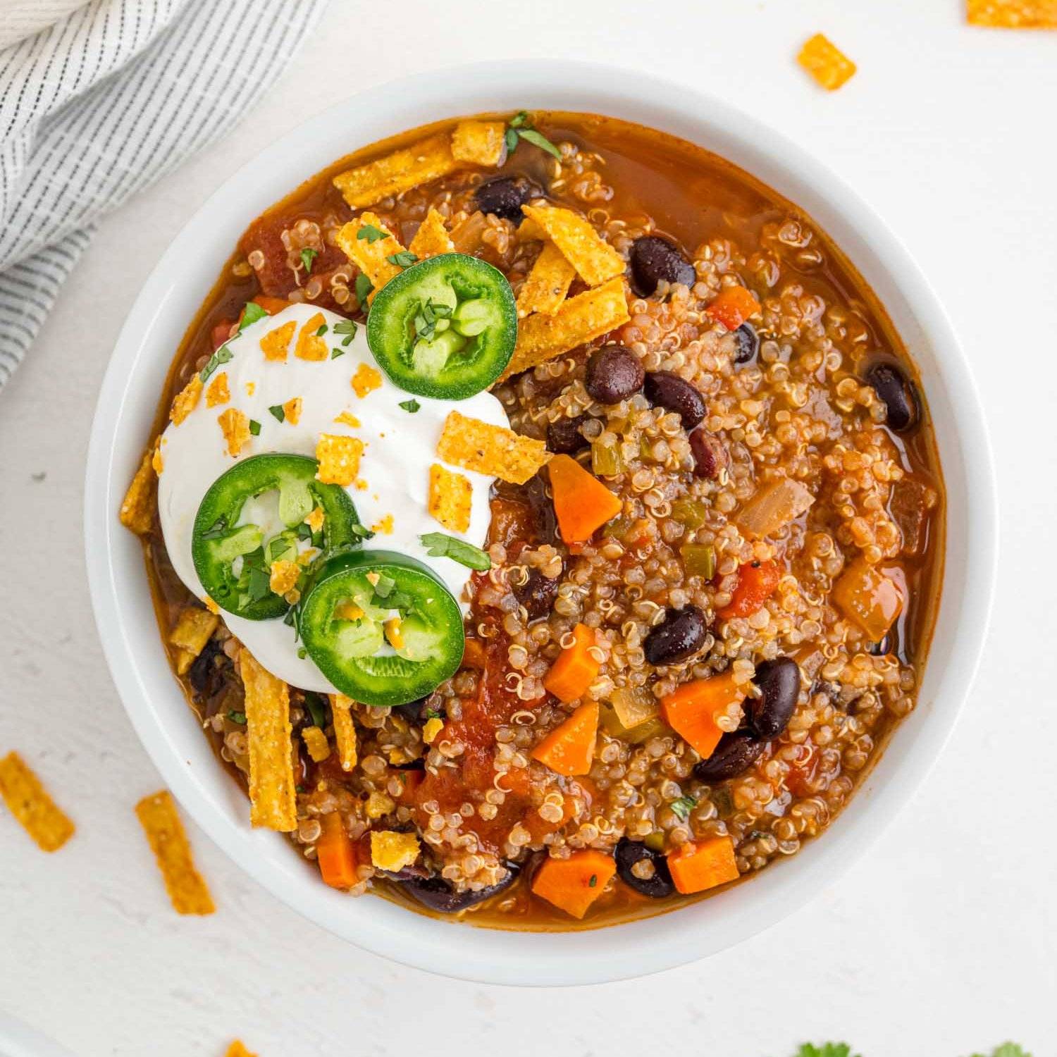 Vegetarian quinoa chili topped with sour cream, tortilla strips, and jalapeno slices.