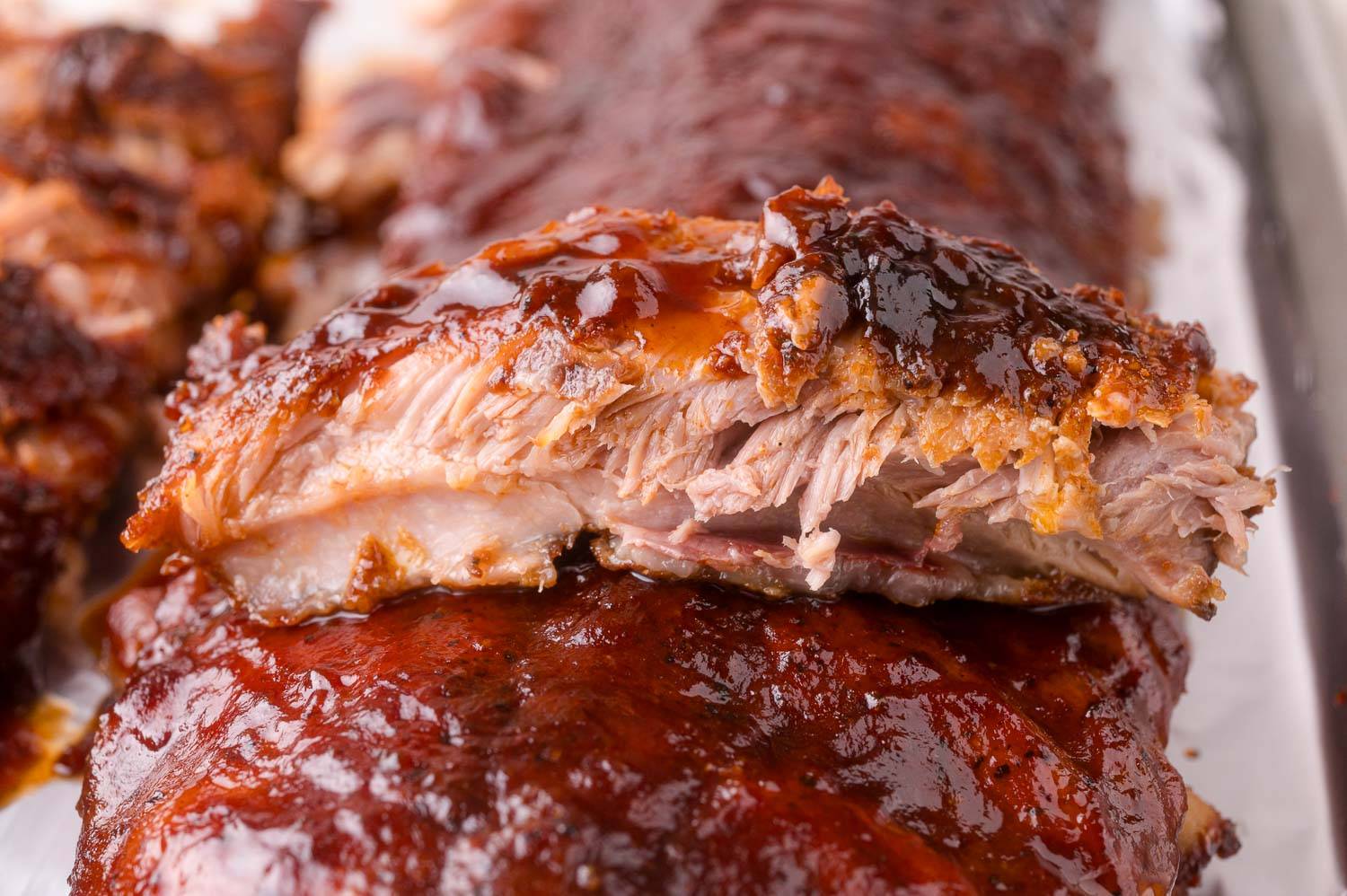 One rib set on top of a rack of barbecued ribs. 