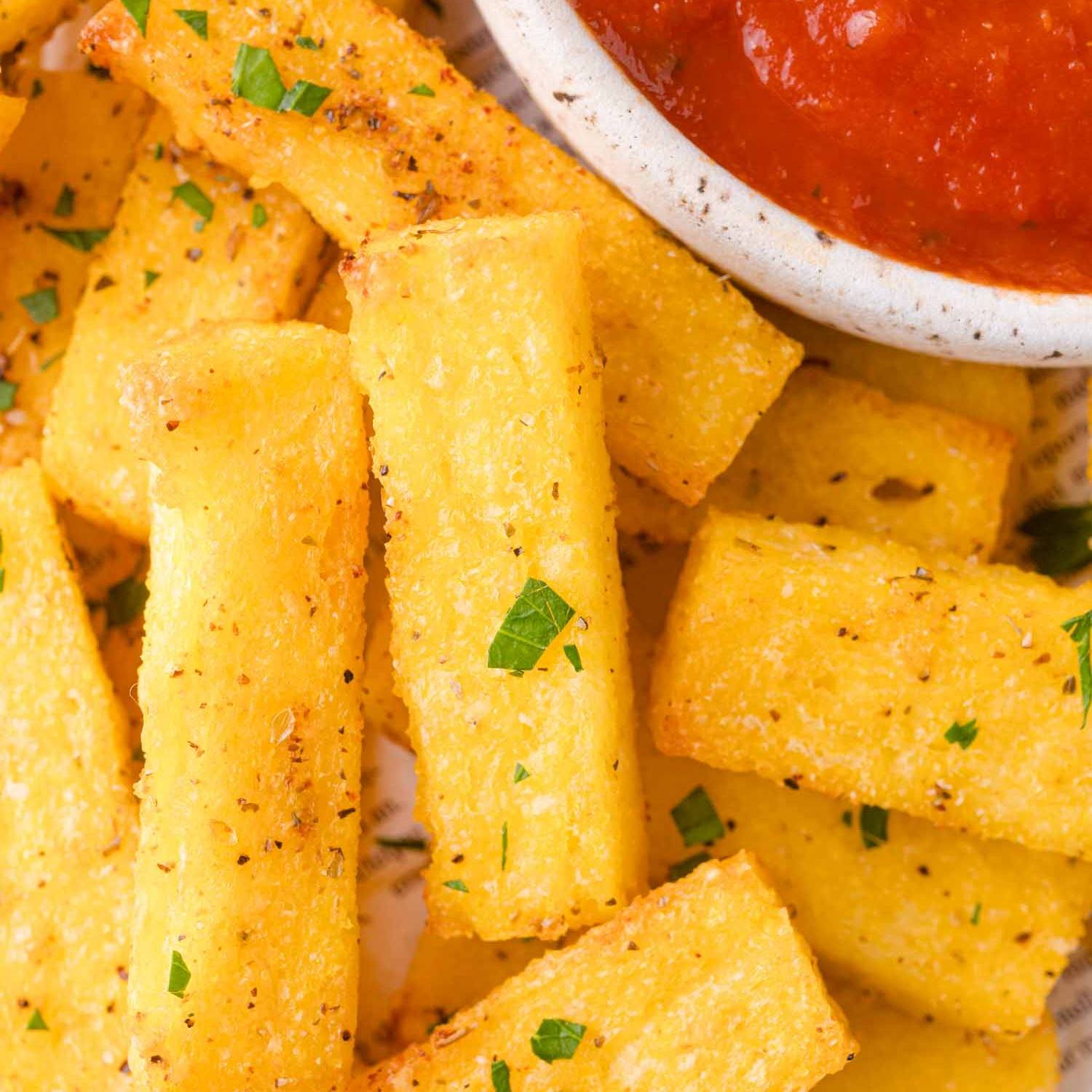 Polenta fries in a pile, bowl of marinara partially visible.