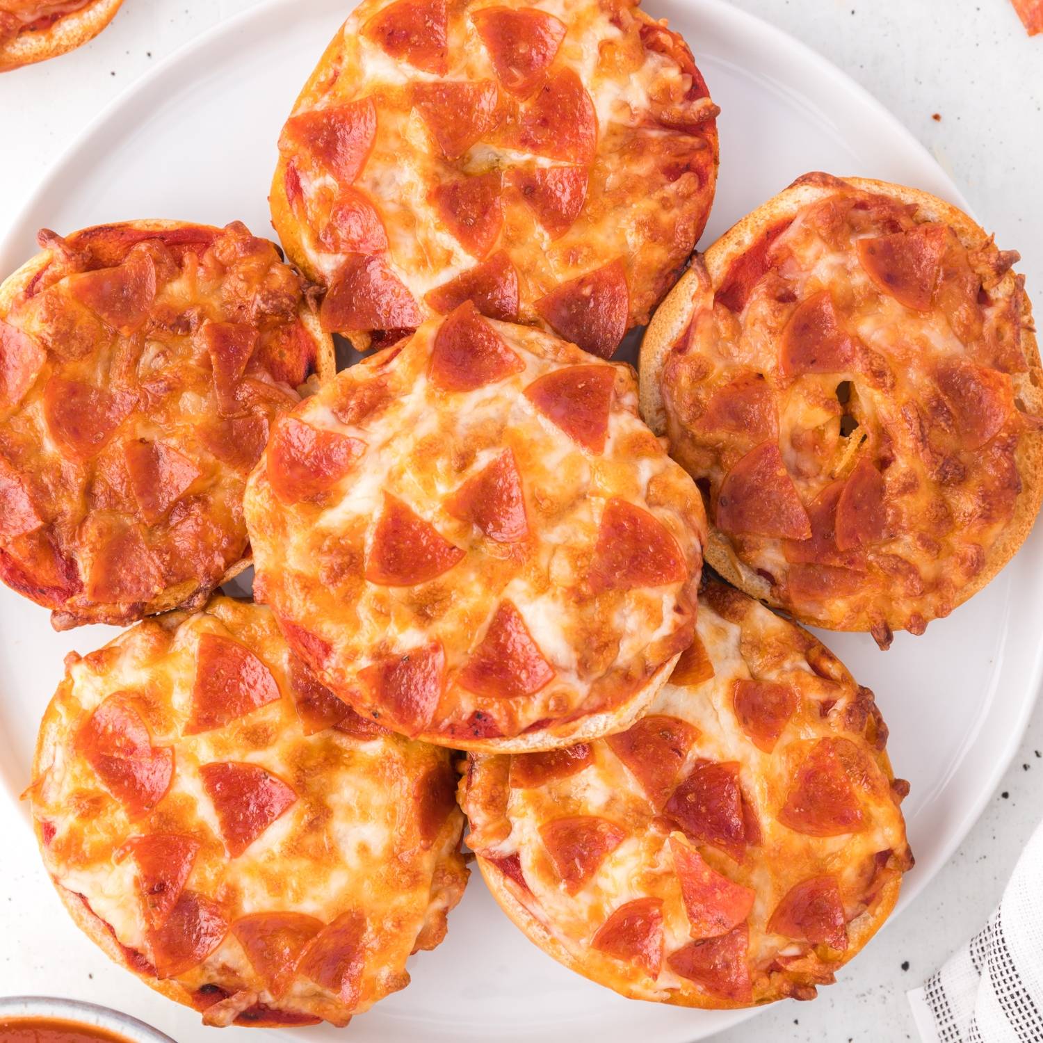 Six air fryer bagel bites on a small white plate.