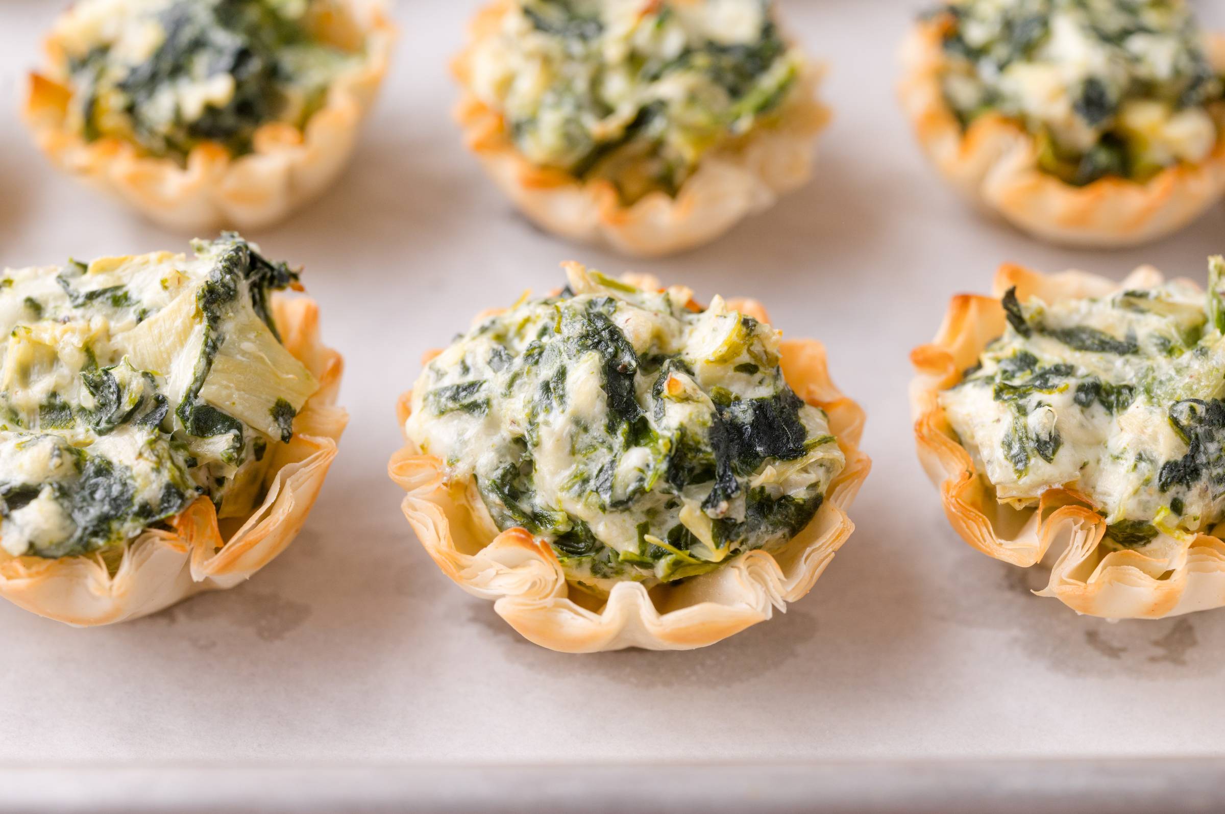 Spinach artichoke bites on a white surface.