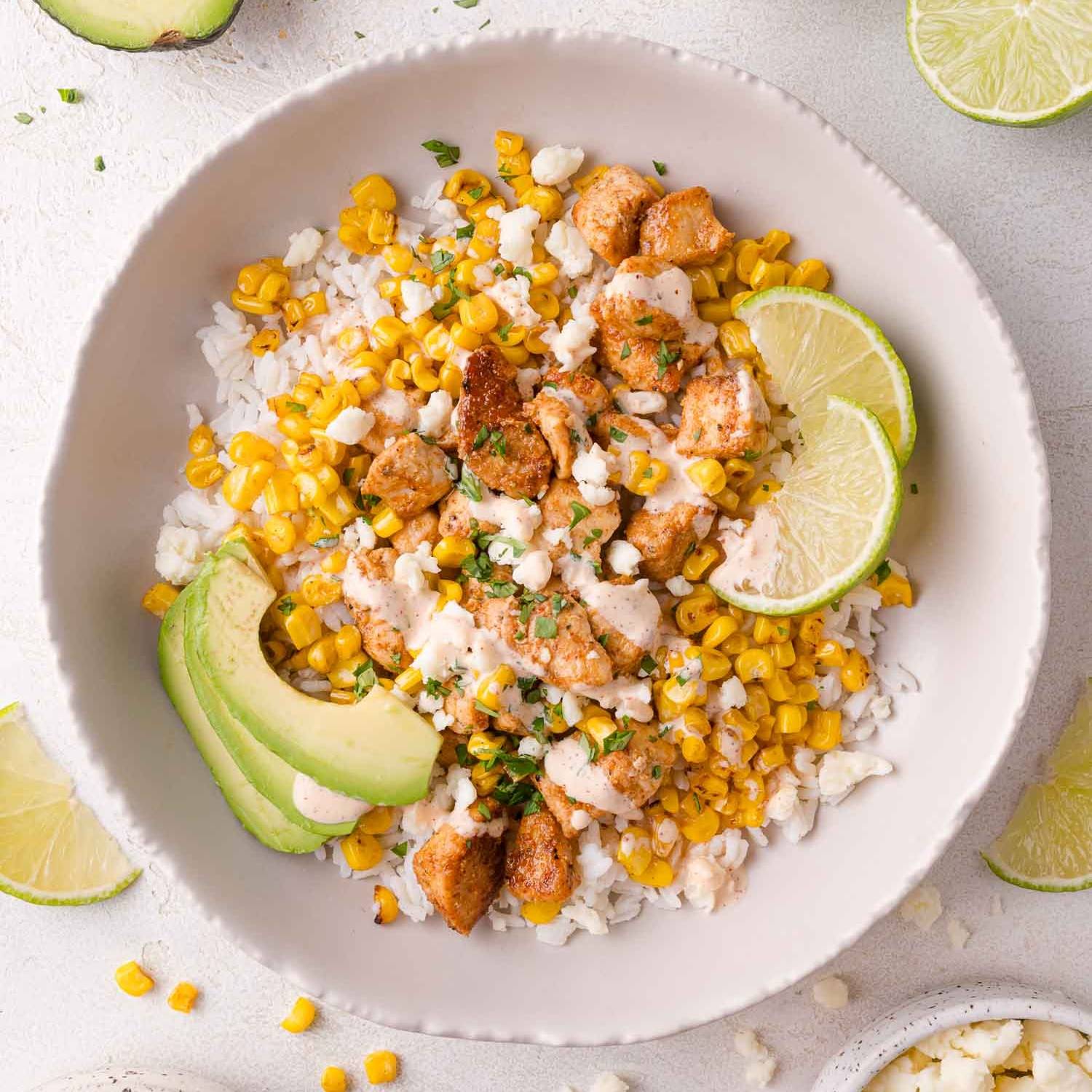 Street corn chicken bowl with rice, chicken, corn, avocado, and a creamy sauce.