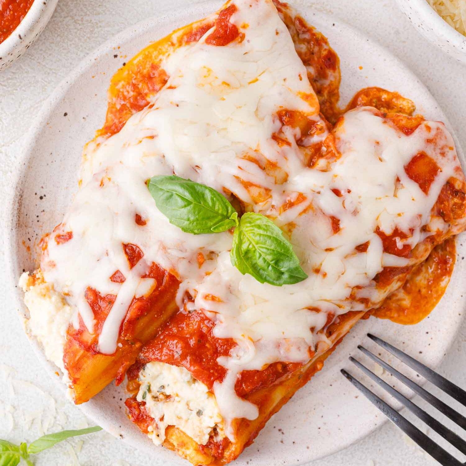 Two tubes of manicotti on white plate.