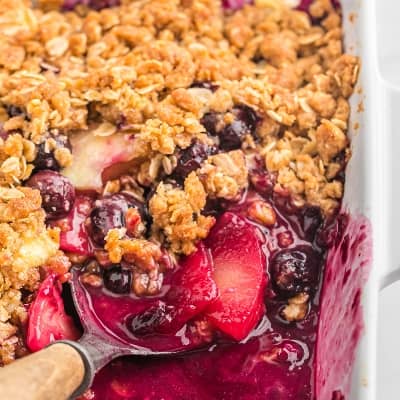 Apple blueberry crisp with a scoop removed.