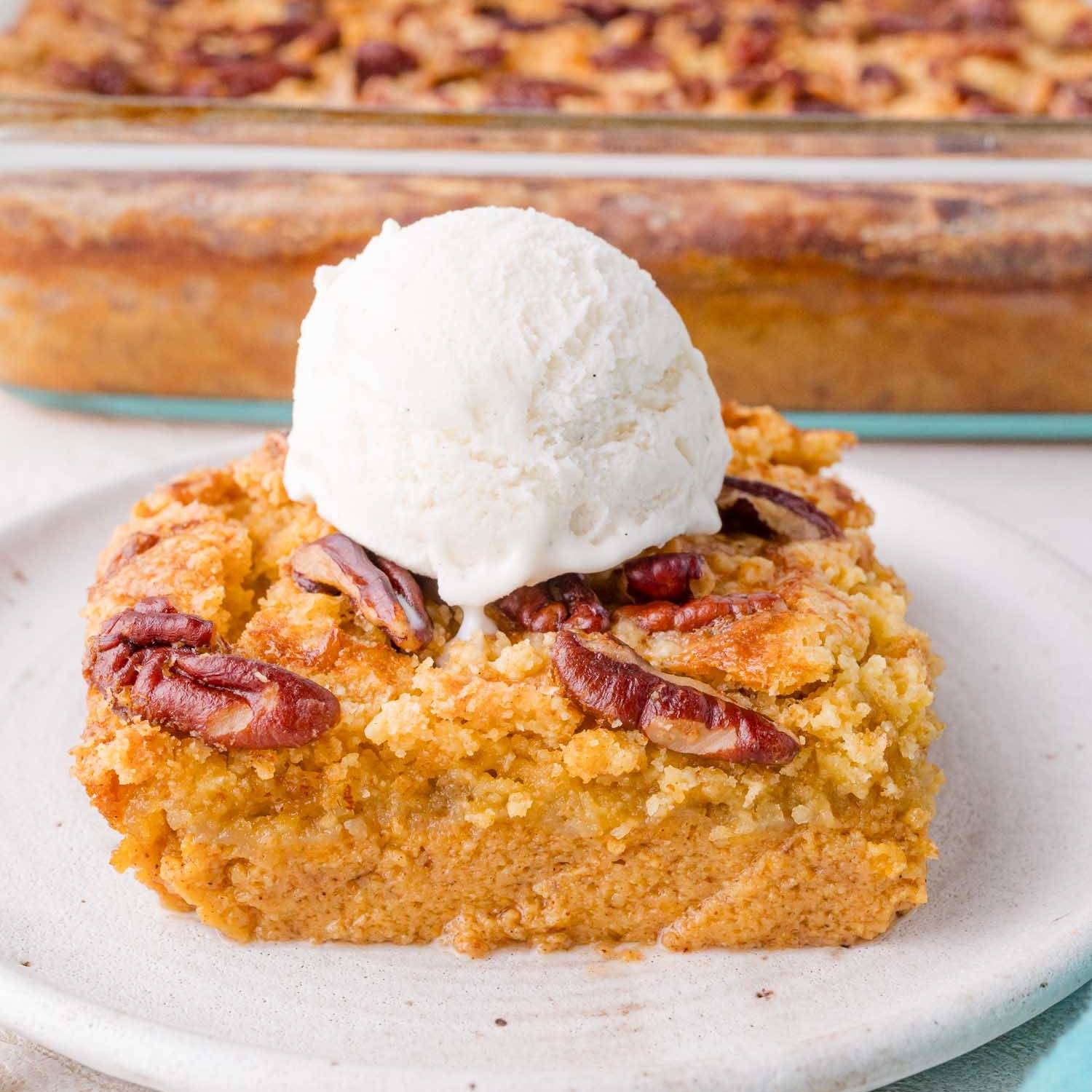 Slice of pumpkin dump cake topped with a scoop of ice cream.