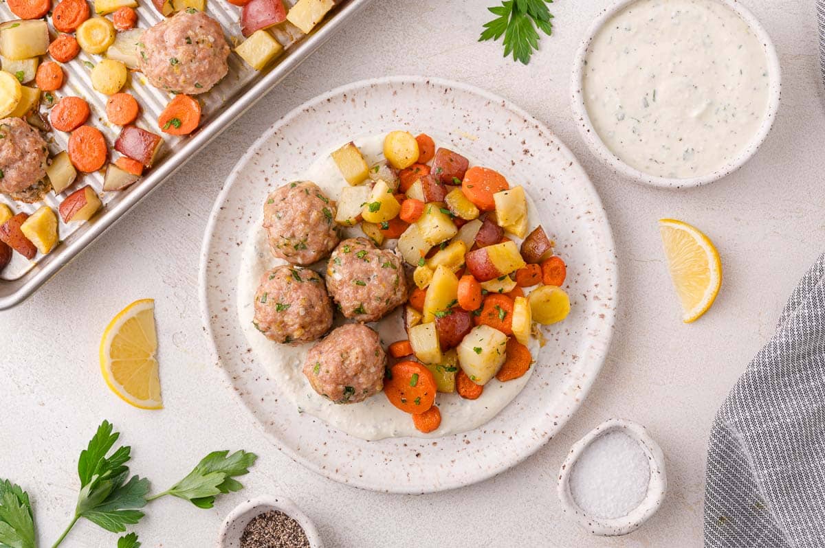 Turkey meatballs and roasted root vegetables on a plate with a creamy white sauce.