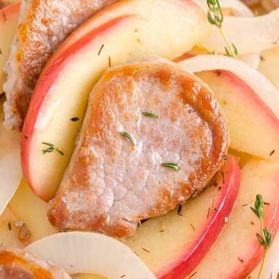 Browned slice of pork tenderloin, with cooked apples and onions.