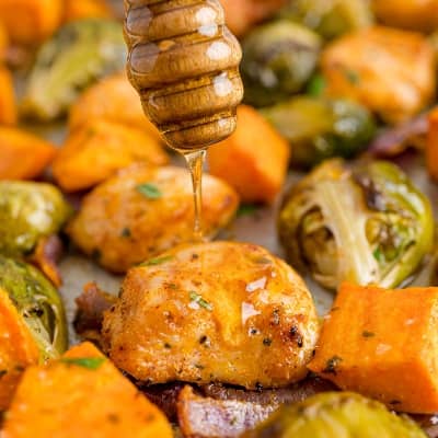 Chicken and vegetables being drizzled with honey.