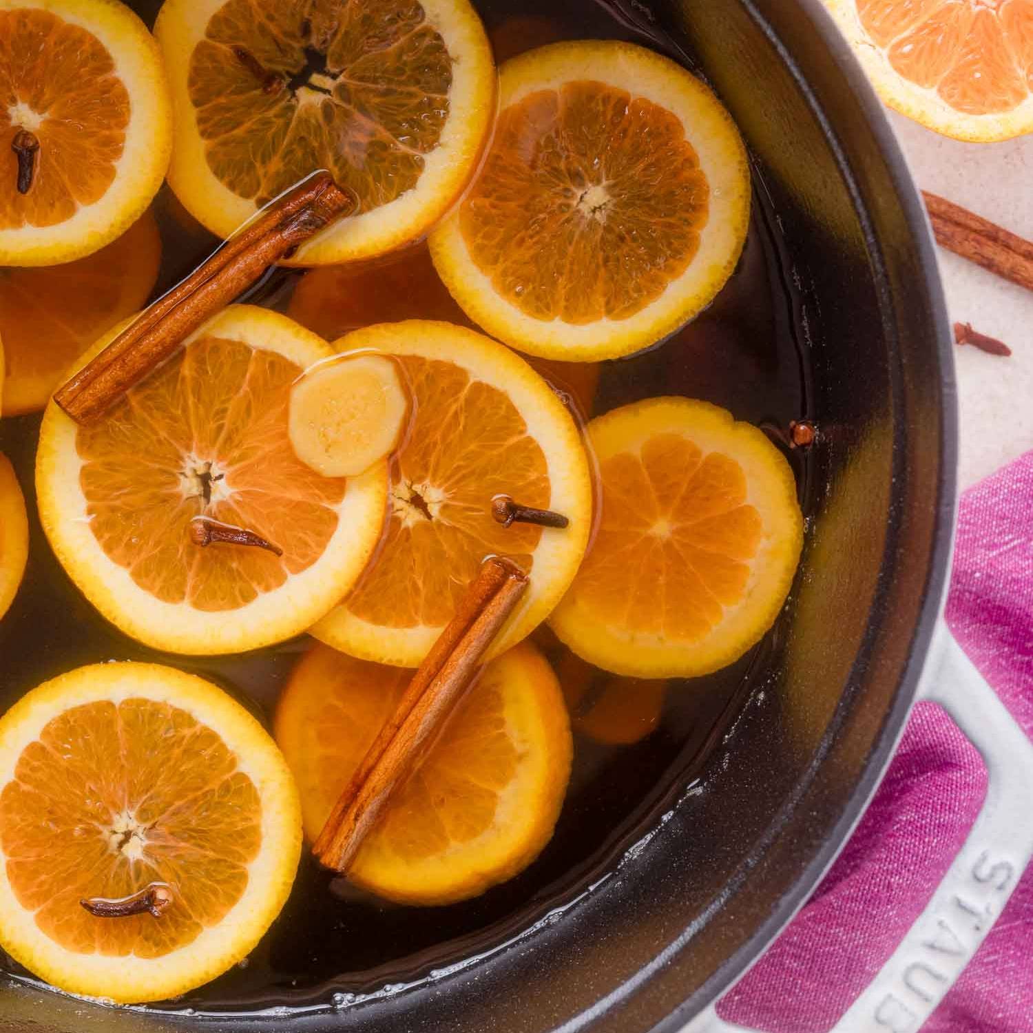 Overhead view of mulled apple cider in a pot with orange slices, cinnamon sticks, cloves.