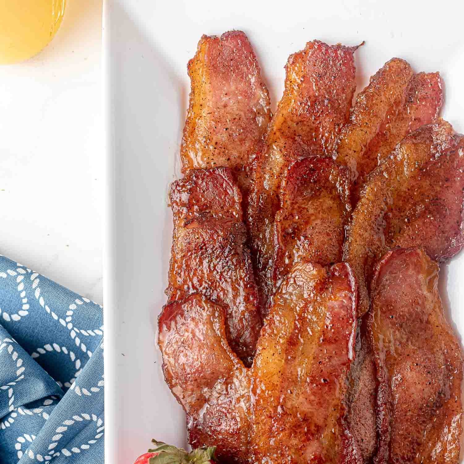 Candied bacon on a white platter.