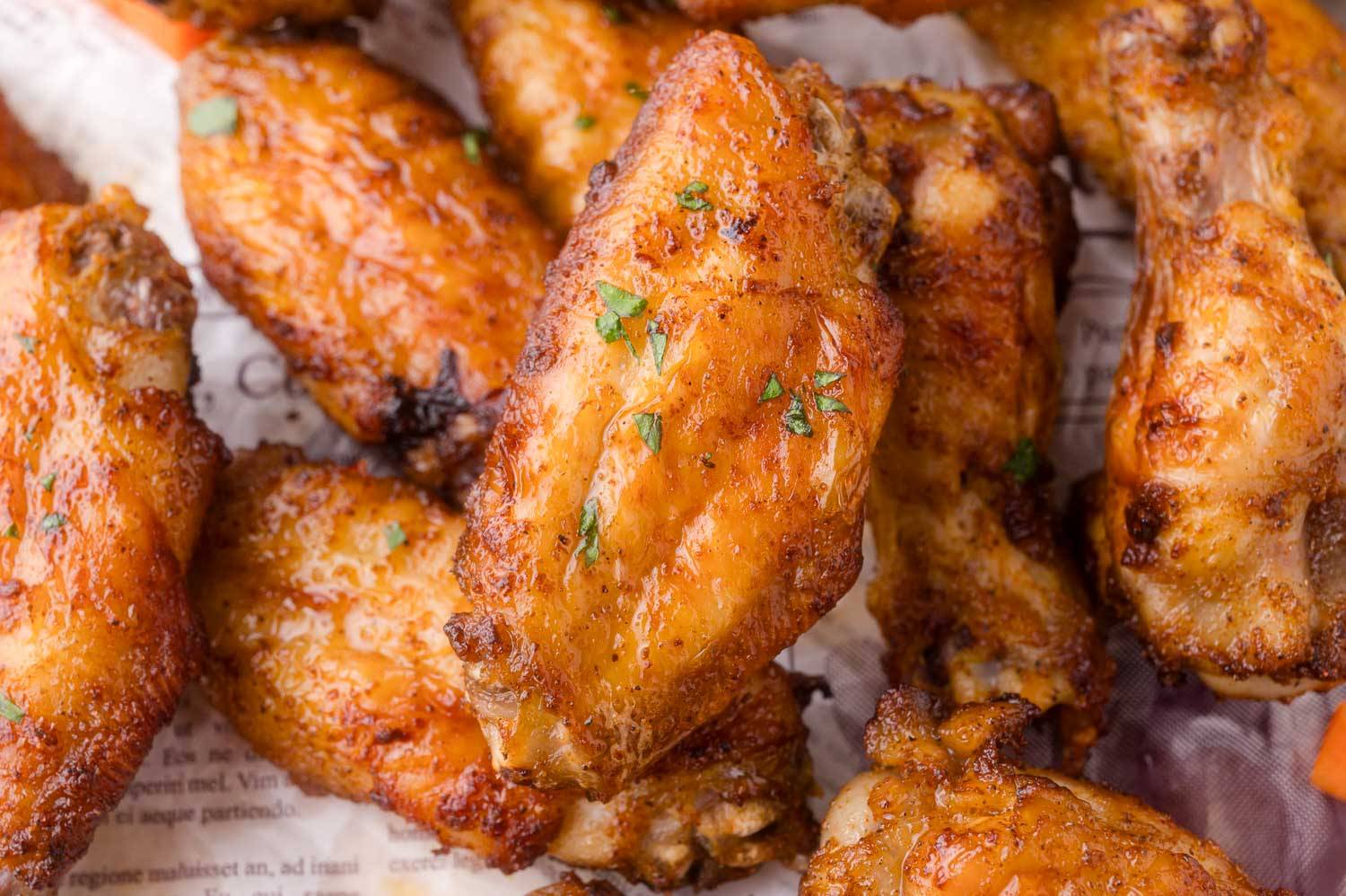 Air fryer chicken wings sprinkled with minced parsley, on a newspaper background.