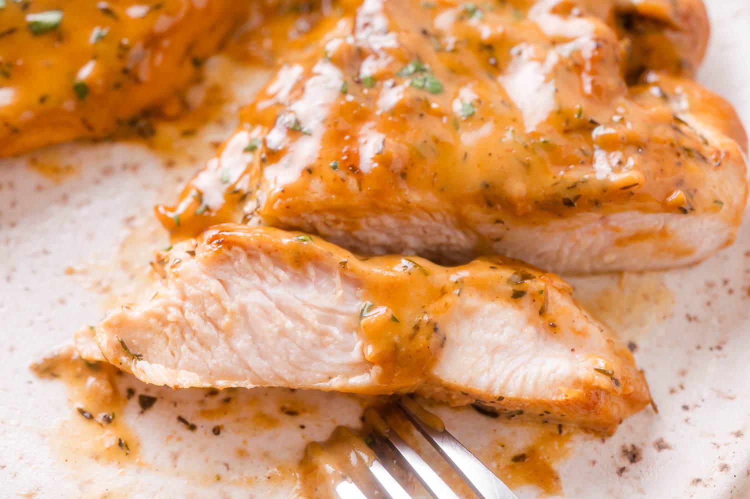 Sliced chicken with a dark brown sauce made from cream and apple cider, with flecks of thyme.