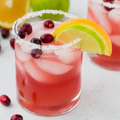 Light pink drink in a salt rimmed glass with cranberries.