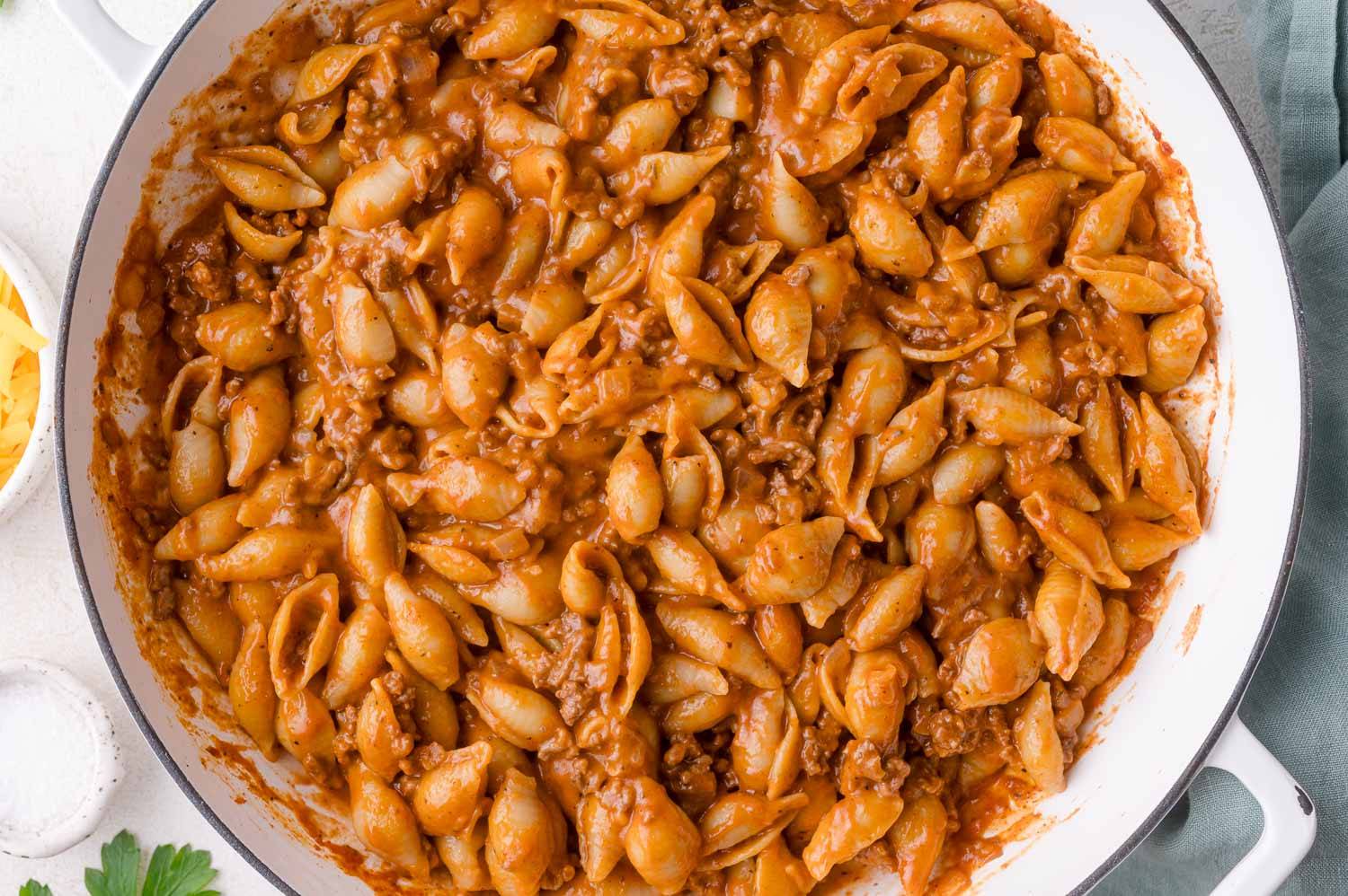 Creamy beef and shells in a white pot.