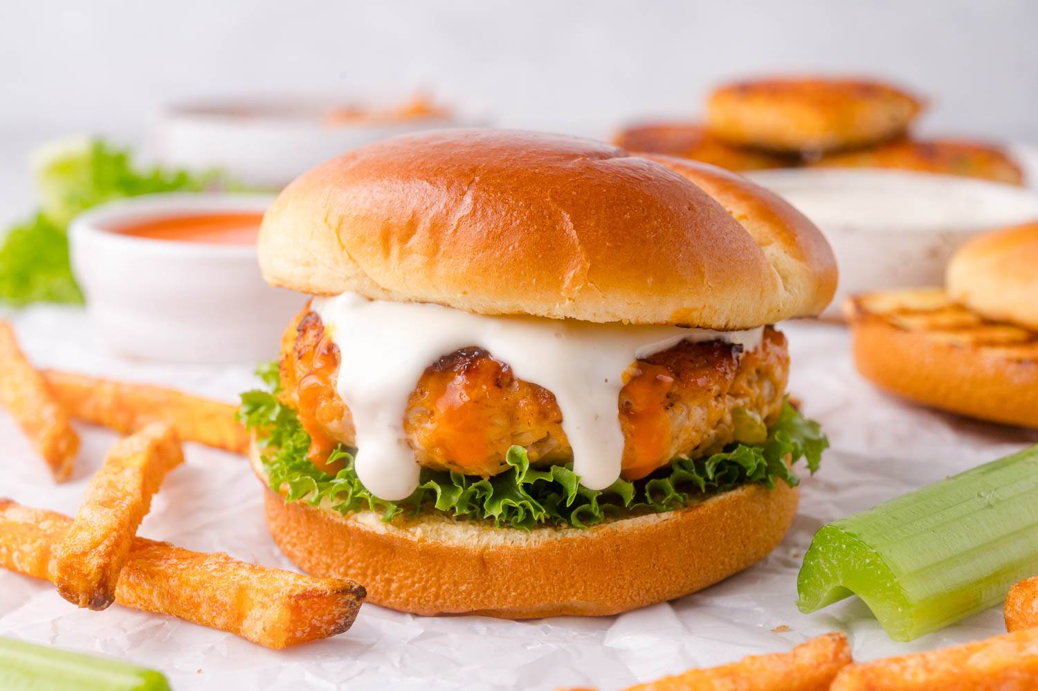 Buffalo chicken burger on a bun with ranch and lettuce.