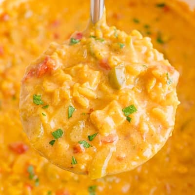 Mulligatawny soup in a ladle, held over a pot with more soup.