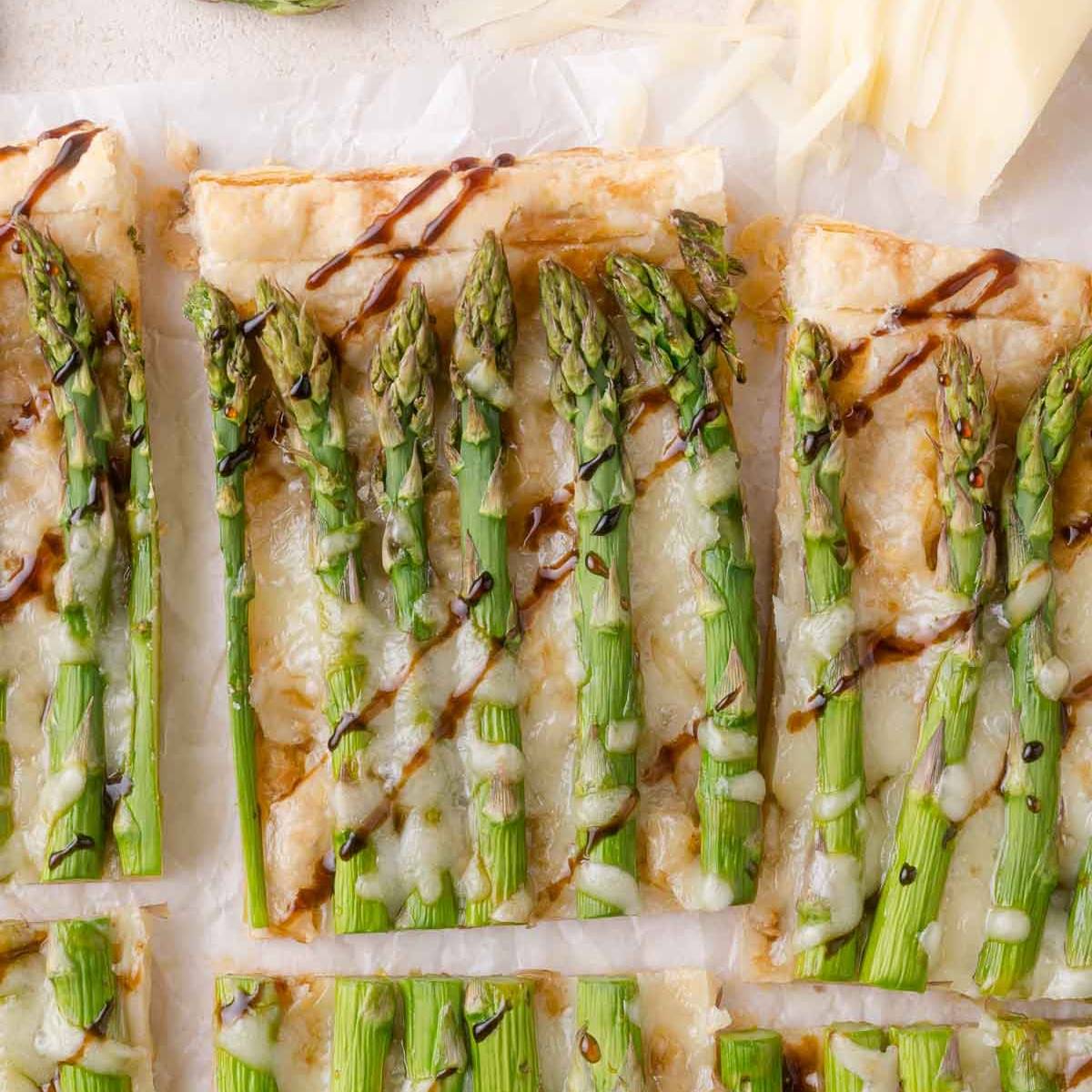 Puff pastry tart with asparagus and cheese on top, drizzled with balsamic glaze.