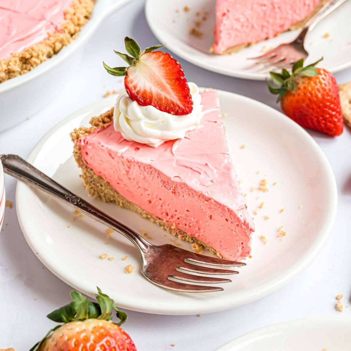 Kool-Aid pie, light pink in color, on a white plate, topped with whipped cream and a strawberry.