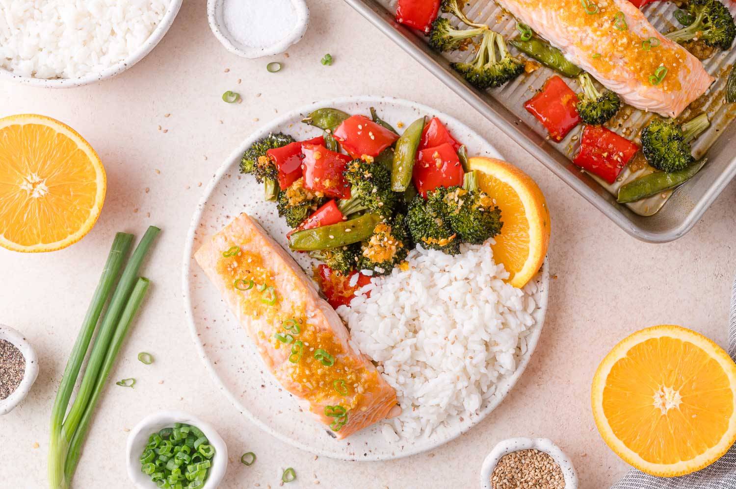 Orange ginger salmon on a plate with roasted vegetables and steamed rice.