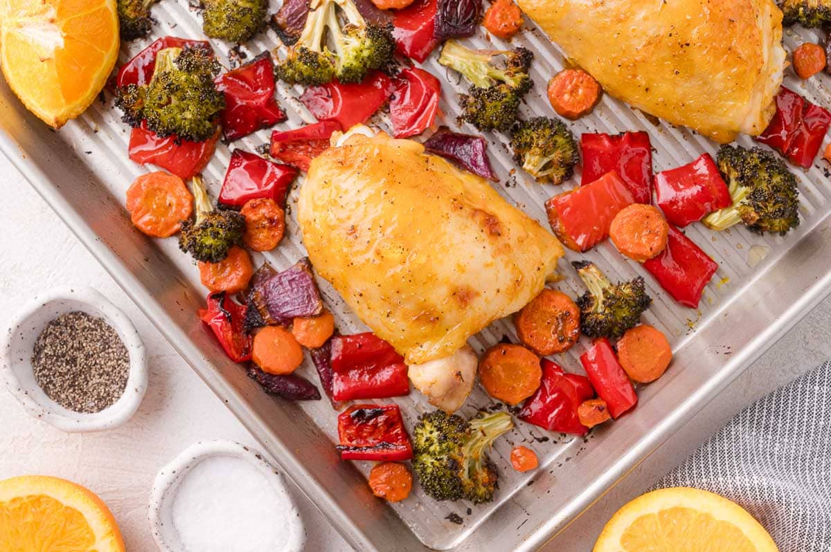 Chicken thighs and colorful vegetables on sheet pan.