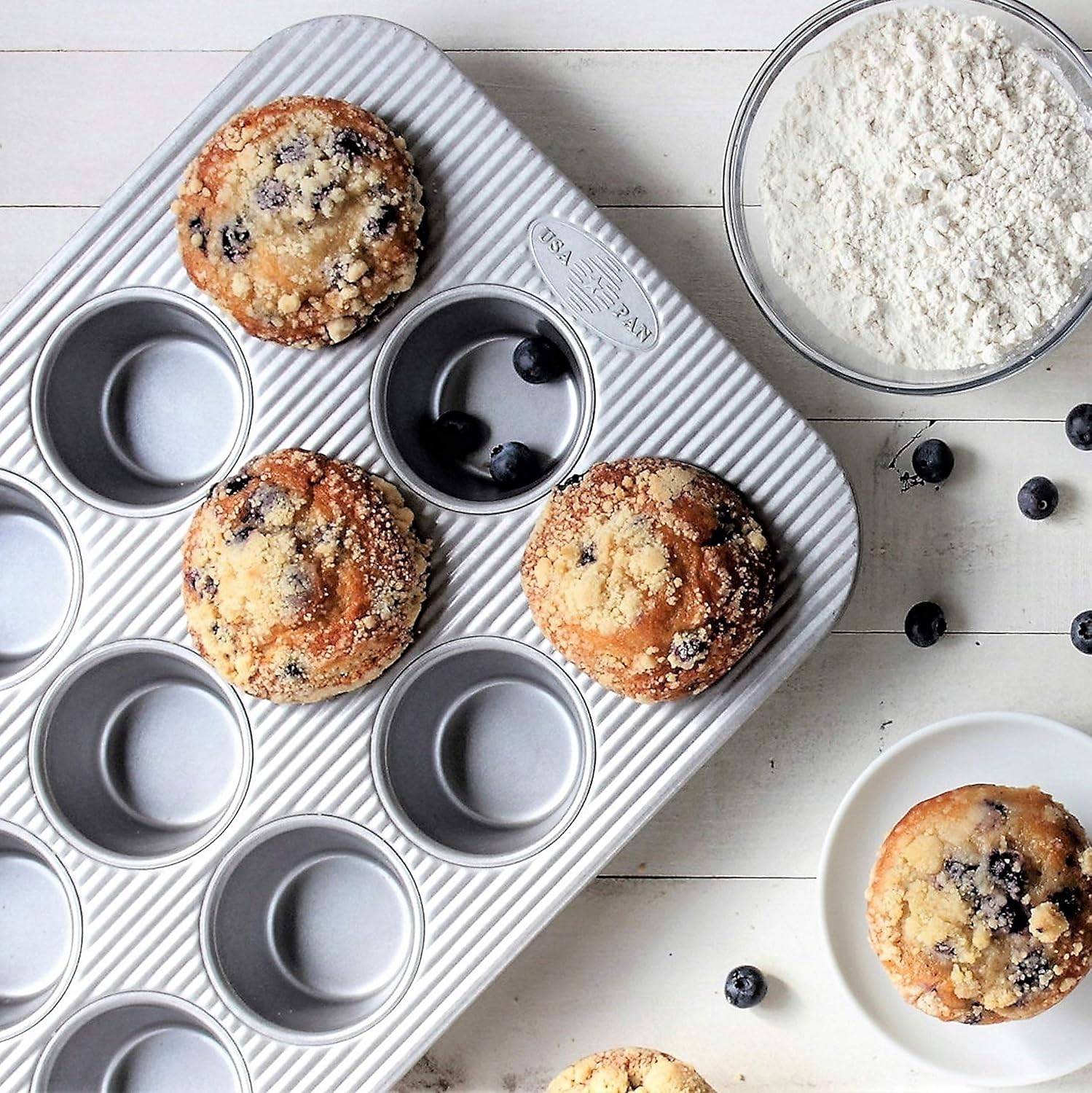 Overhead view of muffin pan with three blueberry muffins in it.