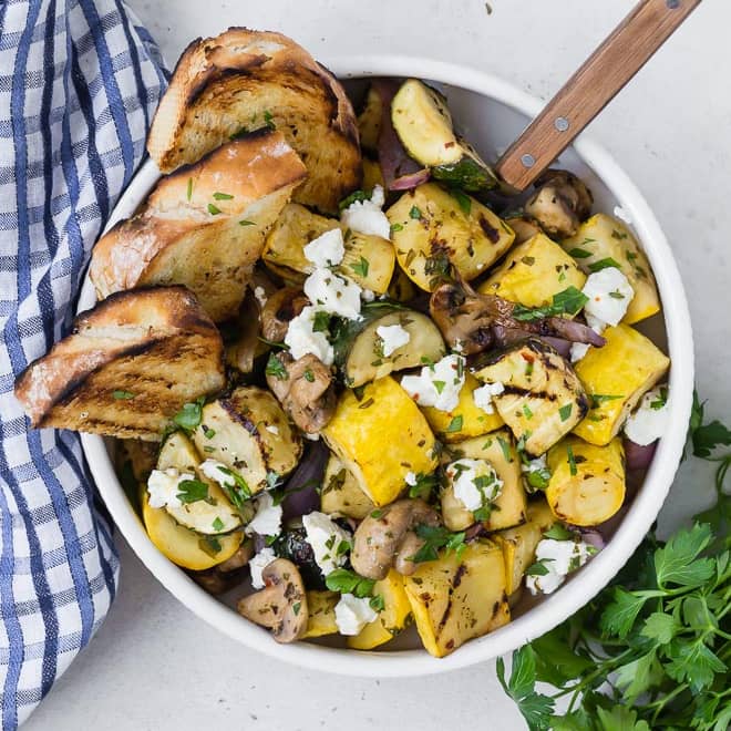 Grilled vegetables in a bowl with grilled bread.