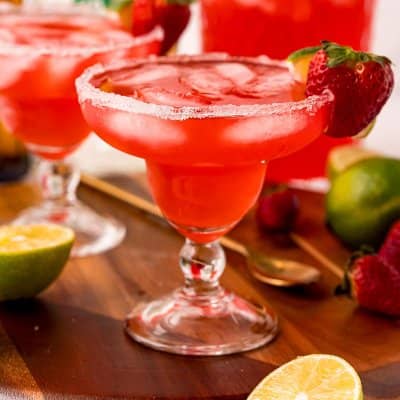 Strawberry margarita in a margarita glass, garnished with a sugar rim and a strawberry.