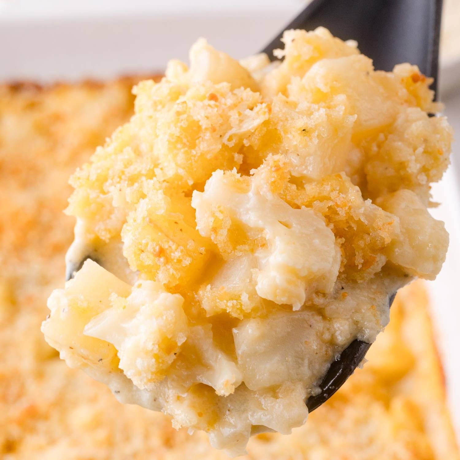 Cauliflower potato casserole being scooped with a black spoon.