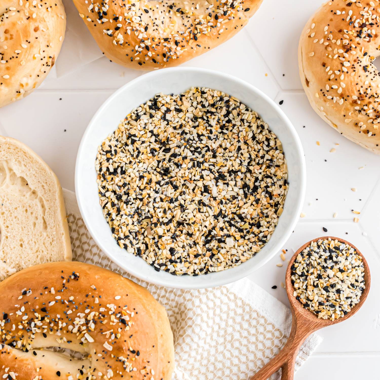 Everything bagel seasoning in a bowl, surrounded by bagels.