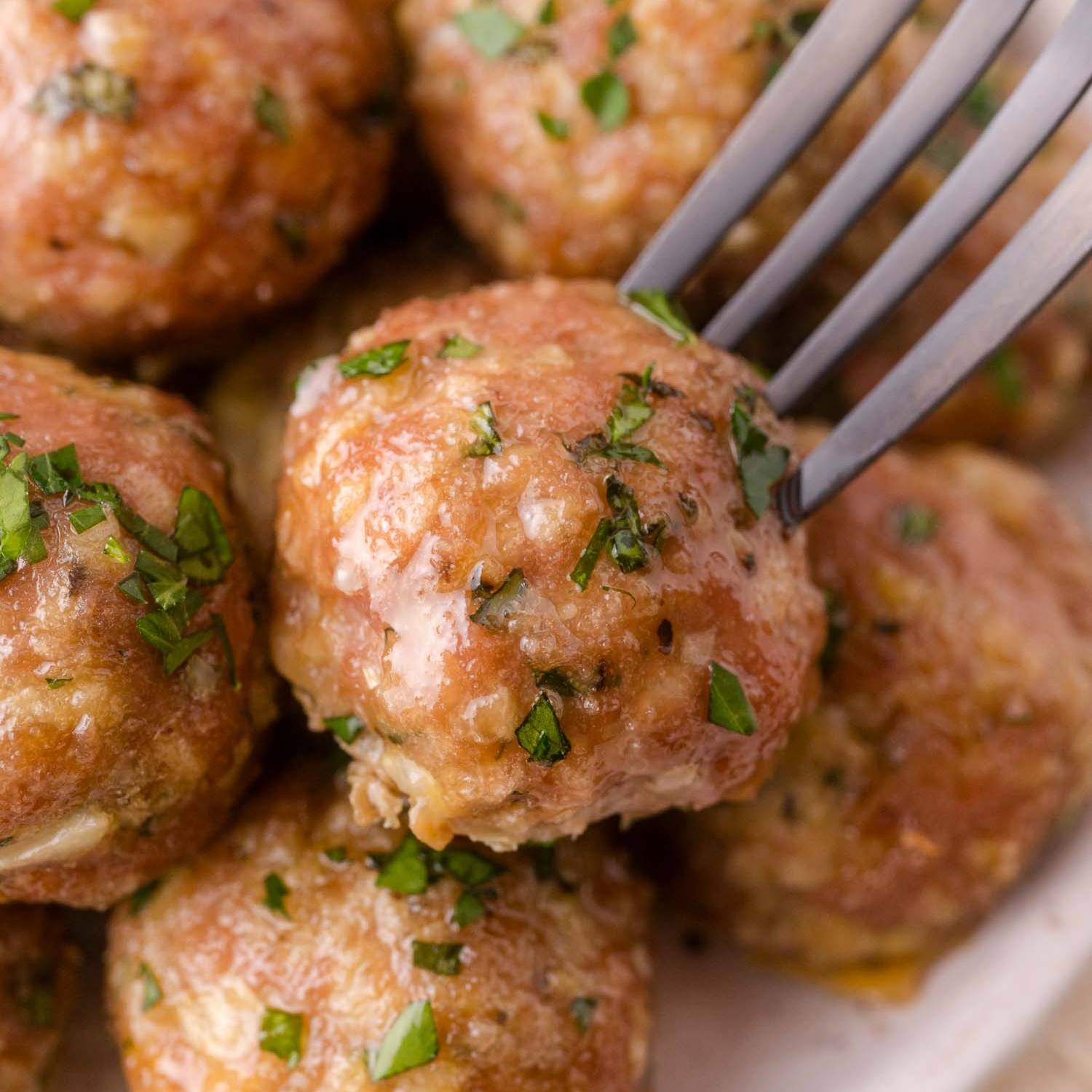 Baked turkey meatballs, one being picked up with a fork.