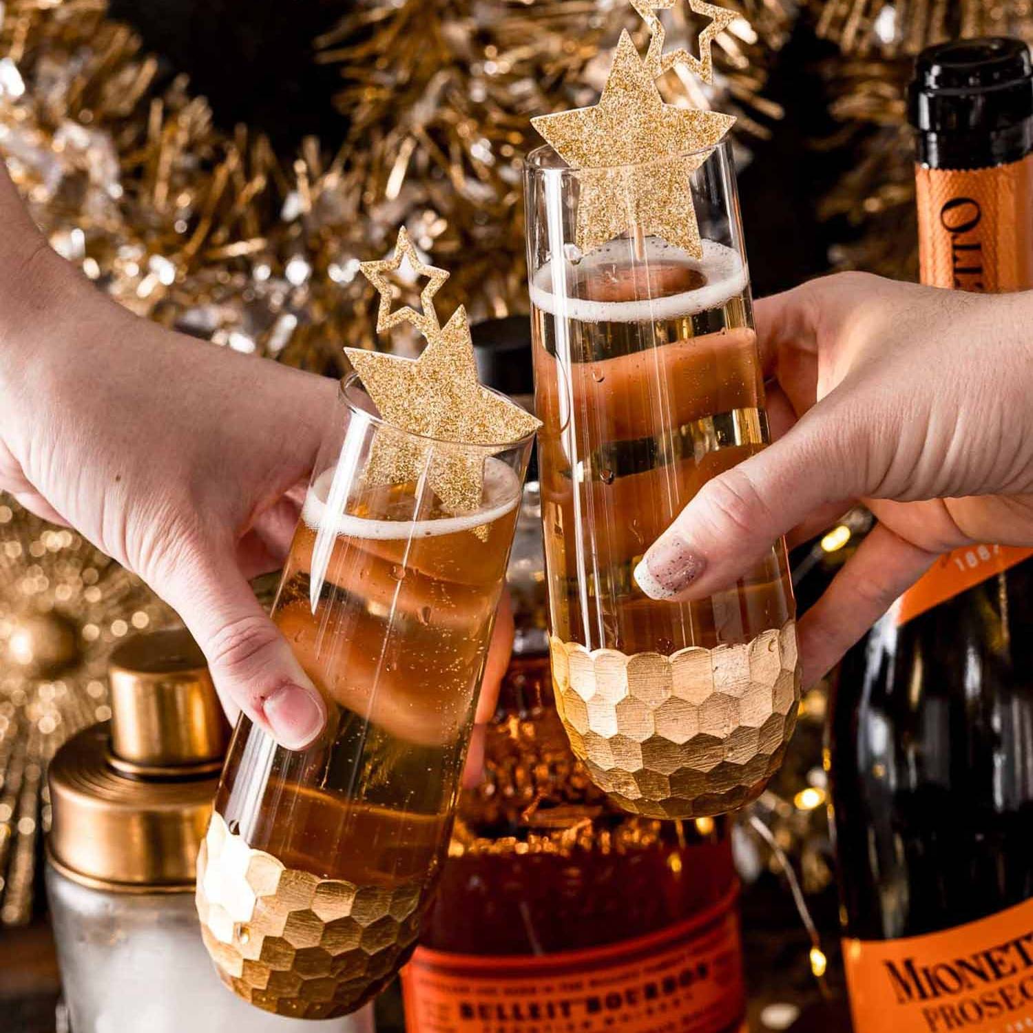 Two glasses of vanilla bourbon fizz being brought together.