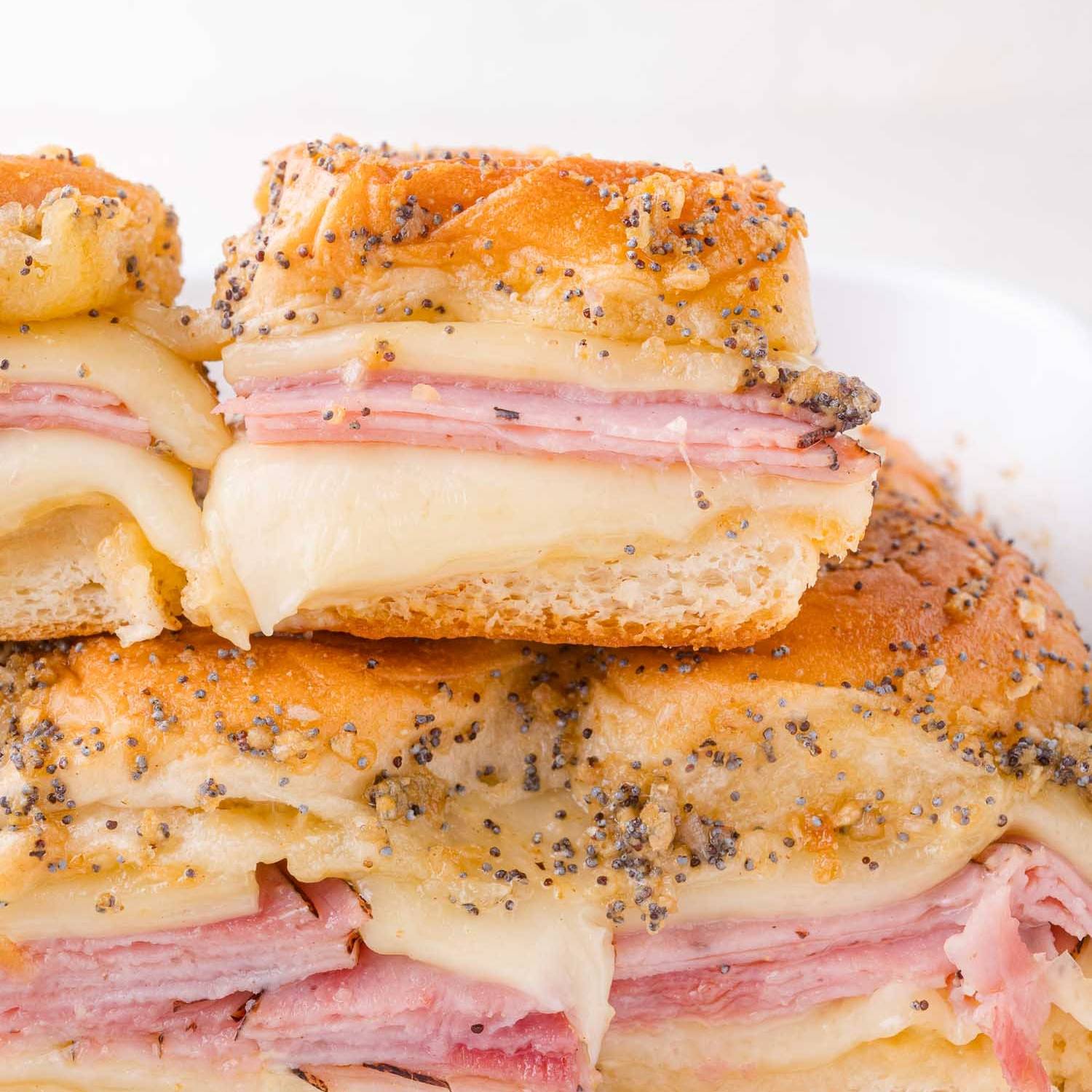 Ham and cheese sliders stacked on top of more sliders.