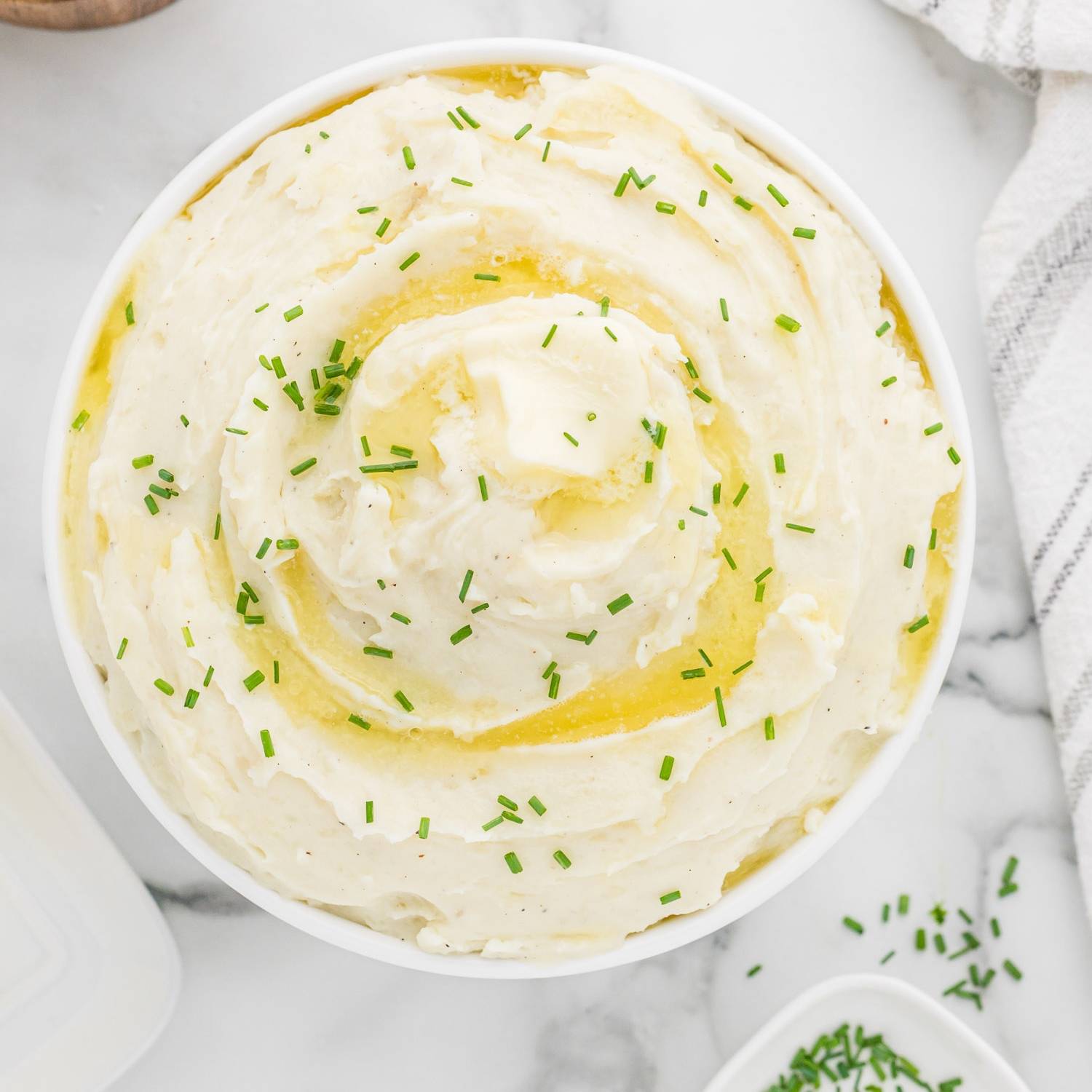 Large bowl of mashed potatoes with butter and chives.
